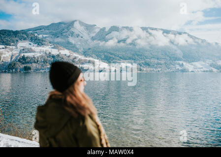 Frau am Seeufer mit schneebedeckten Bergen im Hintergrund Stockfoto