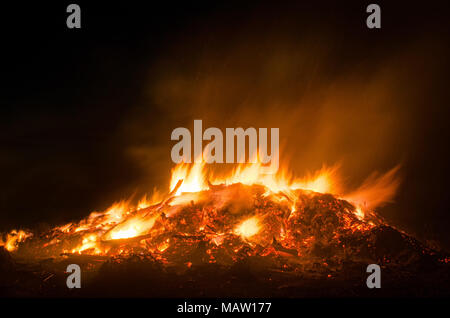 Ausbrechende Feuer flammen aus einem riesigen Osterfeuer in den ländlichen Nacht Stockfoto