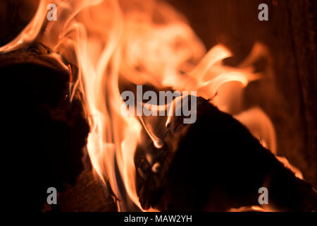 Orange heißes Feuer Flammen im Kamin mit fast schwarzen Hintergrund Stockfoto