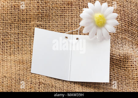Weiße leere Karte auf braunen Sack mit weißen Blume Hintergrund ihr Design zu ersetzen. Stockfoto