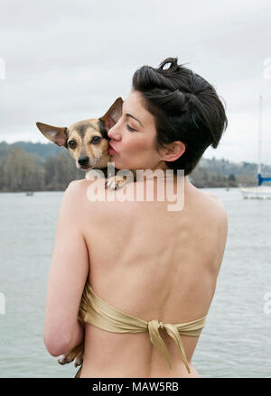 Eine Frau, die auf einem Dock auf dem Willamette River ihr Hund Holding, eine Chihuahua mix. Stockfoto