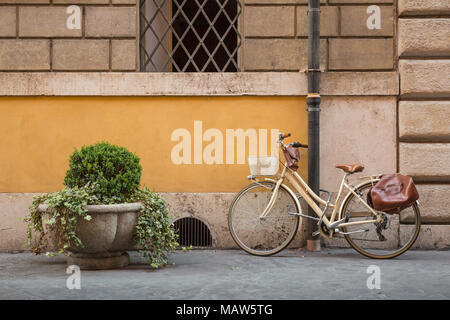 Ein cremefarbenes retro style Fahrrad mit braunen Beutel bis zu einem Abflussrohr auf einer Straße in Rom, Italien gesperrt. Stockfoto