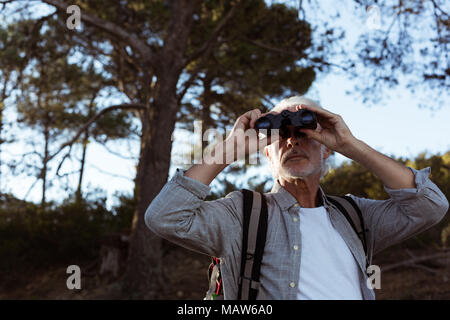 Ältere Wanderer durch ein Fernglas im Wald suchen Stockfoto