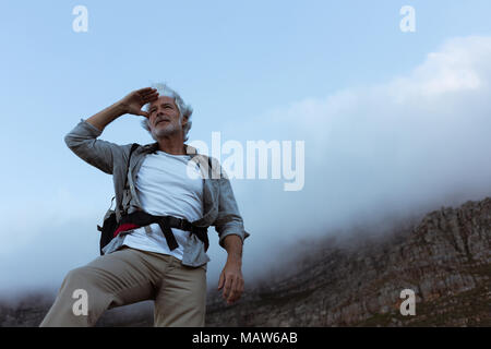 Ältere Wanderer Abschirmung Augen auf einem Berg Stockfoto