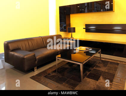 Modernes Wohnzimmer mit Ledersofa und gelben Wänden Stockfoto
