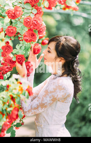 Die Seite Portrait der Braut berühren und duftende rote Rosen. Stockfoto