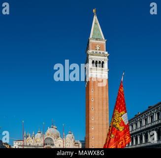 Geflügelte Löwe von St. Markus, die Venezianische Flagge an der Piazza San Marco in Venedig mit den San Marco, Campanile Tower. Stockfoto