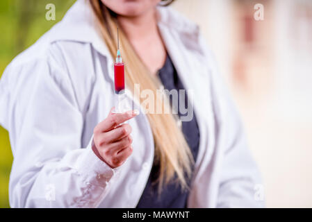 Nahaufnahme von Frau trägt einen Laborkittel und halten eine Spritze mit Blut in Ihrer Hand Stockfoto