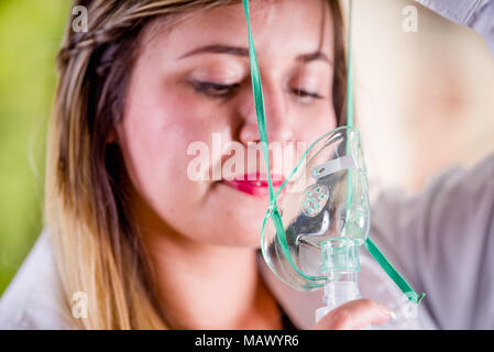 Porträt der jungen schönen Frau mit Zerstäuber für Asthma und Erkrankungen der Atemwege Stockfoto