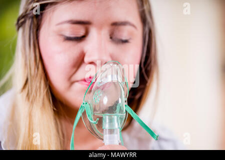 Porträt der jungen Frau mit Zerstäuber für Asthma und Erkrankungen der Atemwege zu Hause Stockfoto