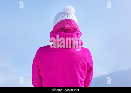 Detailansicht zurück zu von der jungen Frau in rosa Winterjacke stehen auf dem Gipfel des Berges. Stockfoto