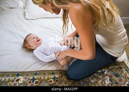 Eine Mutter mit ihren 10 Monate alten Sohn spielen auf einem Bett. Stockfoto