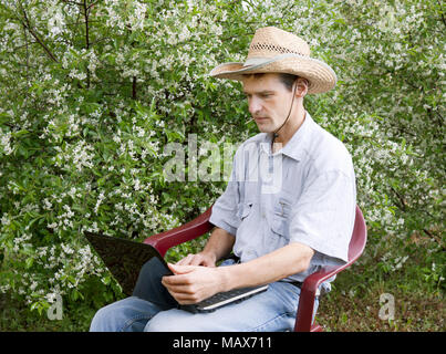 Ein junger Mann in einer Kirsche Garten im Frühjahr Stockfoto