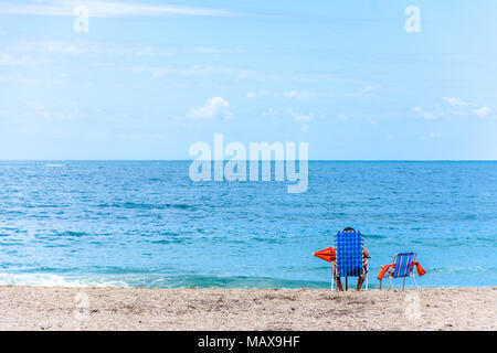 Florianopolis, Brasilien. Februry, 2018. Stuhl, Schirm und eine Person am Strand am Horizont über dem Meer. Stockfoto