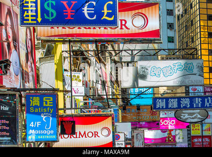 Eine bunte Reihe von Schildern hängen über einer belebten Kowloon Straße. Kowloon, Hongkong. Stockfoto