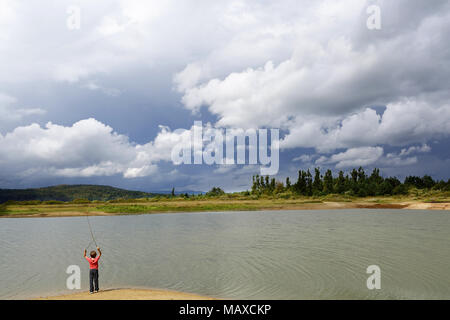 Junge beim Spielen mit holzstöcken am Ufer eines trockenen See Stockfoto