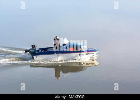 Kleines Motorboot langsam auf ruhigem Wasser Stockfoto