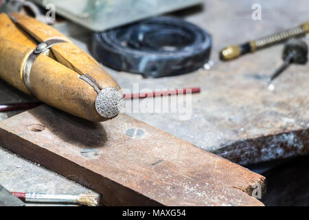 Ein silberner Ring auf einer hölzernen ring Schelle auf einem jewerly Workbench auf einem Workshop platziert. Stockfoto