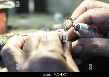 Männliche Juwelier polieren ein silberner Ring mit einem kupferdraht Bürste auf einem flex Welle montiert. Stockfoto