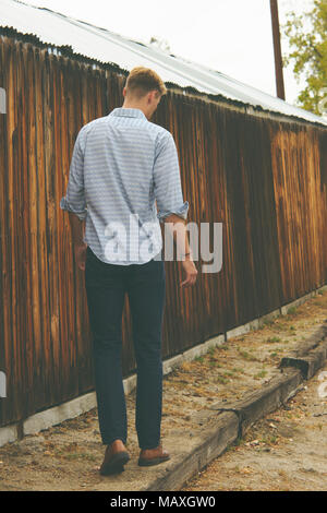 Ein kaukasischer Mann, schlank, kurze Haare, Blick nach unten, weg gehen, die Kamera zurück. Ein Lebensstil im Freien in voller Länge Porträt Konzept. Stockfoto