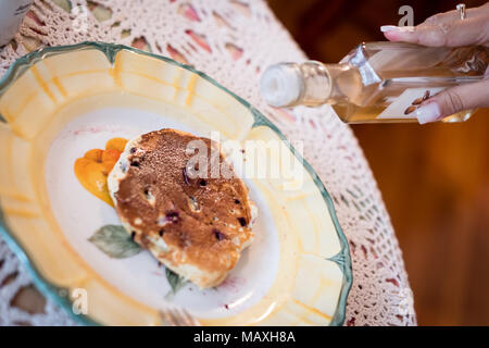 Sirup von womans Hände auf hausgemachten Blueberry pancake gegossen, schönen verzierten Platte, authentische Umgebung. Holz- Hintergrund, verwischt Stockfoto