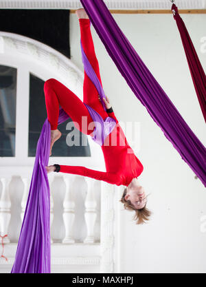 Junge attraktive Luft Gymnast führt eine Übung hängen an aerial Silk Stockfoto
