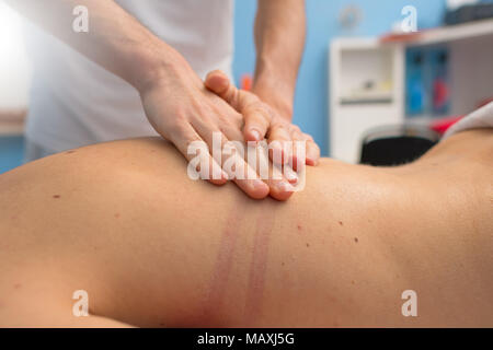 Physiotherapeut führt eine Rückenmassage. Stockfoto