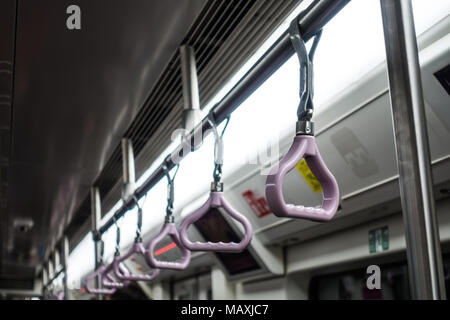 Handgriffe Reihe auf der U-Bahn unter Flourescent leichte asiatische U-Bahn Stockfoto