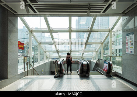 Mädchen, die alleine stehen, die Fenster der städtischen U-Bahn Station absteigend Aufzug in Xi'an, China, 2018 Suchen Stockfoto