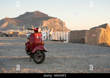 Eine rote Vespa bei Sonnenaufgang, in der Nähe des Hafens in Palermo, Sizilien, Italien geparkt. Stockfoto