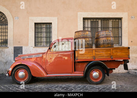 Eine alte rote Fiat 1100 flachen Bett van mit hölzernen Weinfässer im Rücken, außerhalb Ristorante Carlo Menta in Rom, Italien, geparkt. Stockfoto