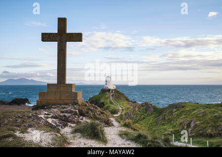 Ansicht der keltischen Kreuz auf Ynys Llanddwyn Insel Angelsey mit Twr Mawr Leuchtturm im Hintergrund Landschaft Stockfoto