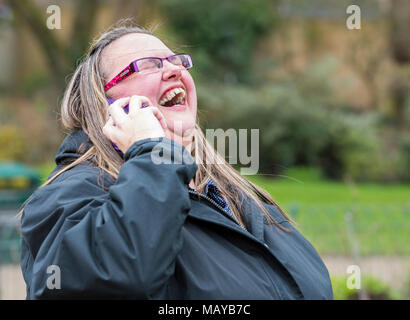 Junge Frau lachend und glücklich, während Sie ein Telefongespräch mit einem Freund. Glück Konzept. Mit einem Lachen. Lachen mit Freunden. Stockfoto