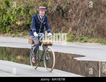 Älterer mann Radfahren auf einem viktorianischen Fahrrad im Zeitraum Kostüm Blazer und Stroh Kreissäge Hut gekleidet, in Großbritannien. Radfahrer reiten vintage Bike. Stockfoto