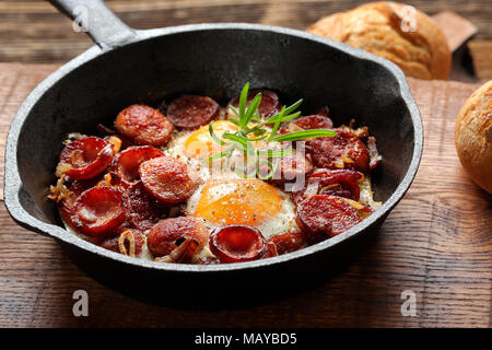 Spiegeleier mit Wurst und Zwiebeln in der Pfanne Stockfoto