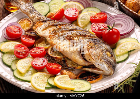 Gebratene dorada Fisch mit Gemüse auf hölzernen Hintergrund Stockfoto