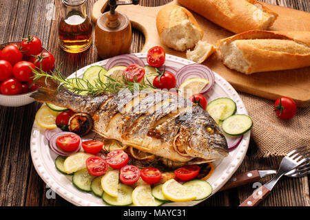 Gebratene dorada Fisch mit Gemüse auf hölzernen Hintergrund Stockfoto