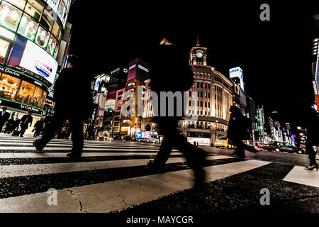 Tokio, Japan. Fußgänger überqueren der Straße im Herzen von Ginza in Tokio. Ginza Kreuzung bei Nacht. Verschwommene Bewegung. Stockfoto