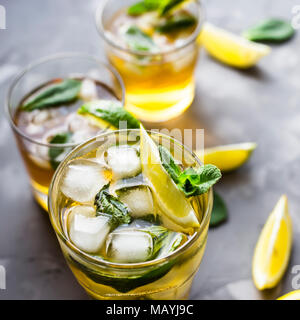 Ein paar Glas Gläser mit einem kalten Kaffee mit Eis, Minze und Zitrone auf grauem Beton Hintergrund. Im Sommer Kühlung trinken Stockfoto
