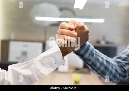 Afrikanische und kaukasische Handshake im Büro in Corporation Erfolg Stockfoto