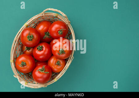 Organische frische reife rote Tomaten in Weidenkorb auf Türkis Grün leuchtende Hintergrund. Italienisch Spanisch Griechisch-mediterrane Küche. Gesunde Ernährung Lebensmittel I Stockfoto