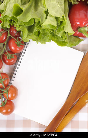 Auswahl an Salat Gemüse mit leeren Rezeptbuch oder Shopping Liste auf eine Tischdecke. Stockfoto