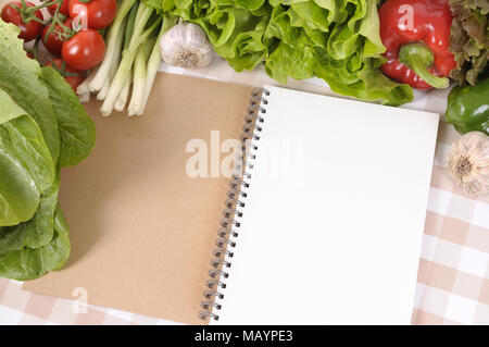 Auswahl an Salat Gemüse mit leeren Rezeptbuch oder Notebook auf eine Tischdecke. Stockfoto