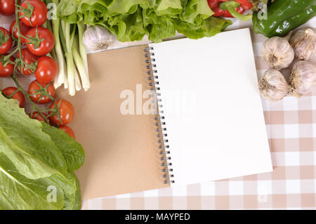 Auswahl an Salat Gemüse mit leeren Rezeptbuch oder Notebook auf eine Tischdecke. Stockfoto