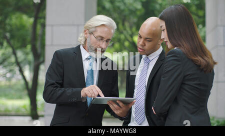 Multinationale Unternehmen Führungskräfte diskutieren Geschäft mit digitalen Tablet. Stockfoto