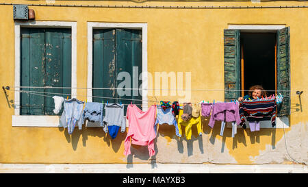 Ältere Frau prüft Wäsche trocknen auf Seile außerhalb ihres Fensters gestreckt, Venedig, Venetien, Italien Stockfoto
