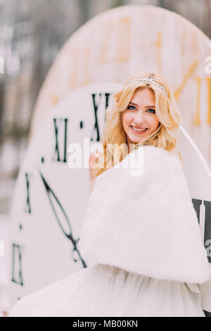 Schönen blonden Braut an der großen Vintage Uhren im Herbst Wald. Kreative Hochzeit Dekorationen Stockfoto