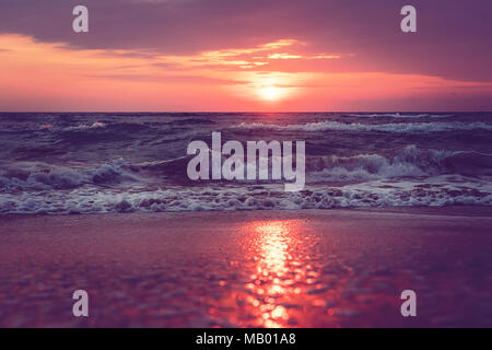 Einen schönen Sonnenaufgang auf Sanibel Island, Florida. Helle intensiv pink lila orange Sonnenaufgang am Meer. Wellen im Morgengrauen. Reflexion von Sonnenlicht in Wasser ein Stockfoto