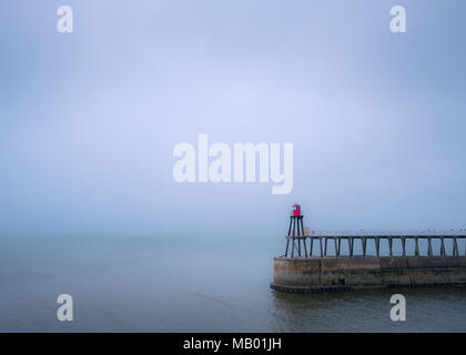 Der Osten Pier und Leuchtturm in Whitby an einem nebligen und verregneten Tag. Stockfoto