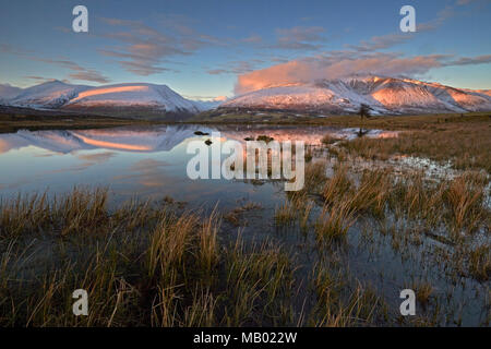 Schnee fiel und Lonscale Blencathra in Tewet Tarn bei Sonnenuntergang wider. Stockfoto